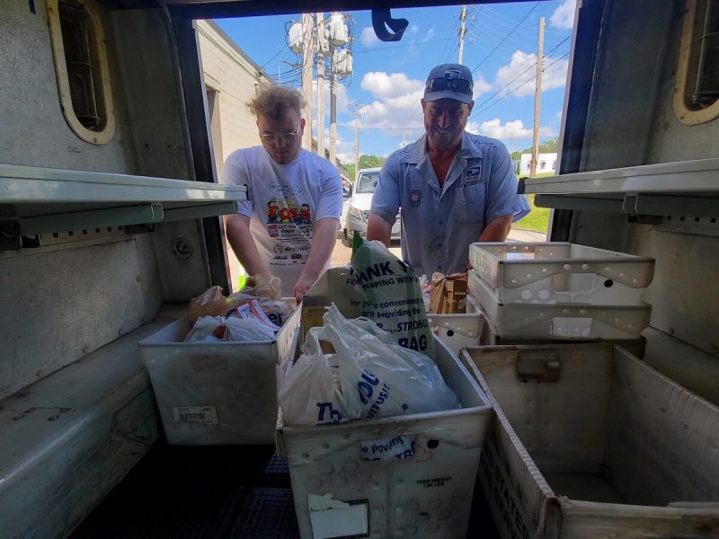 A letter carrier and volunteer unload donations during the 2024 Stamp Out Hunger Food Drive.